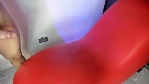 Media: Video of a close-up view of a person's hand holding a red and gray striped object, with a blurred background.