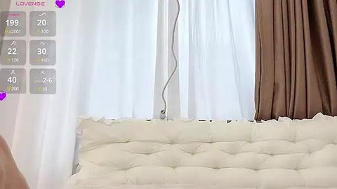 Media: A video of a modern bedroom with a white tufted leather headboard, white curtains, and brown drapes. The left side displays a digital thermometer, showing 29.0\u00b0C.