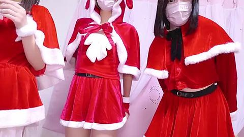 Media: Video of three Asian women in festive red velvet Santa costumes with white fur trim, wearing white masks, holding white papers.