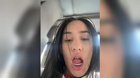 Media: A blurry video of a young woman with long black hair, wearing headphones, looking shocked or surprised with her mouth open.