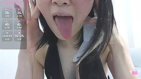 Media: A close-up video of an Asian woman with long black hair, sticking her tongue out. She's wearing a black sleeveless top, with a digital health app interface overlaying the background.