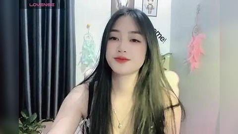 Media: Video of a young Asian woman with long black hair, fair skin, and red lipstick, wearing a black top, in a room with a pink feather and a black curtain, and a \"LOVE NEIE\" watermark.