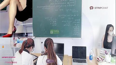 Media: A video depicting a classroom scene with a whiteboard displaying mathematical equations, two women seated, and a woman standing by the board.