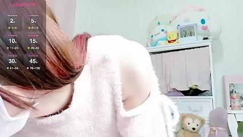 Media: Video of a girl with long, brown hair, wearing a fluffy white robe, in a pastel-colored bedroom with a stuffed bear, a white dresser, and a calendar displaying 15th of the month.