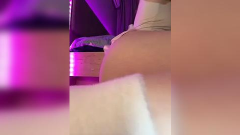 Media: A close-up video of a person's lower body, focusing on the buttocks, wearing white underwear. The background shows a wooden bed frame with a purple glow.