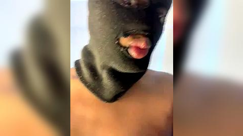 Media: Video of a person wearing a black balaclava, tongue sticking out, with blurred background.