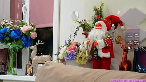 Media: Video of a festive living room featuring a red Santa doll holding a bottle, adorned with a blue floral arrangement, reindeer, and Christmas decorations.