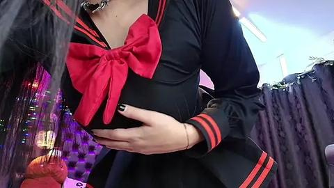 Media: Video of a person in a black sailor uniform with a red bow, holding a pumpkin, in a dimly lit room with purple and orange lights.