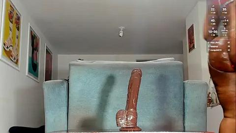 Media: Video of a modern, minimalist bedroom with a large, realistic brown dildo on a light blue couch, surrounded by colorful posters and a digital clock on the wall.