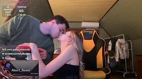 Media: Video of a young couple passionately kissing in a dimly lit room with a black gaming chair and clothes on hangers in the background.