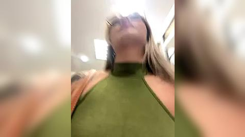 Media: A video of a woman with long blonde hair and a green halter top, taken from a low angle, with a slight blur, creating a dynamic and intimate composition.