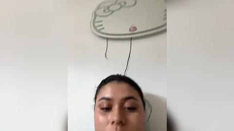 Media: A video shows a woman with dark hair and closed eyes, head tilted back, connected to a white wall with wires, indicating she might be undergoing an EEG test.