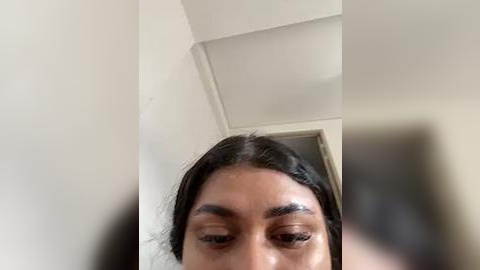 Media: Video of a young South Asian woman with long black hair and brown skin, seen from below, looking upwards. Her eyes are closed, and she has well-groomed eyebrows and neatly trimmed hair.