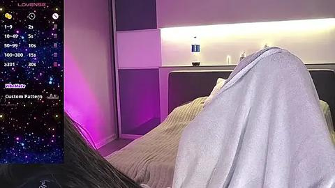 Media: Video of a sleek, modern bedroom with purple and pink LED lights, a cozy gray blanket, and a digital interface displaying customizable options.