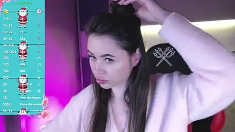 Media: Video of a young woman with long black hair, fair skin, and brown eyes, styled in a white robe, seated against a purple backdrop. She's adjusting her hair with a black cap featuring a skull and crossbones design.