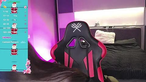 Media: A video of a gamer's setup featuring a black and red gaming chair, a plush bed with black sheets, and a screen displaying a game.