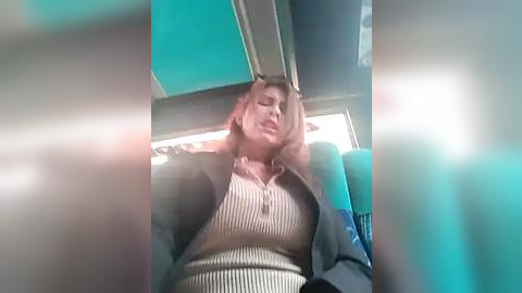 Media: Video of a woman with long brown hair, wearing a striped top, leaning back in a blue seat, eyes closed, on a train, with blurred background.