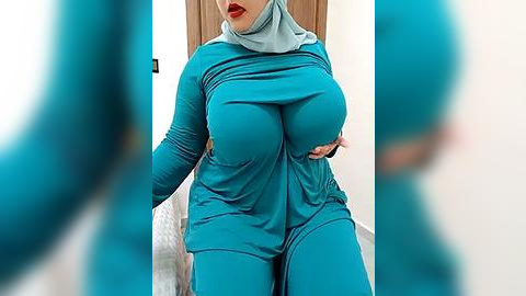 Media: A video of a curvy woman in a tight, teal hijab and matching outfit, sitting on a couch. Her large breasts are prominent, and she has a confident, slightly seductive expression.