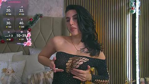 Media: Video of a curvy woman with long black hair in a black glittery dress, standing in a bedroom adorned with Christmas decorations, including a festive wreath.