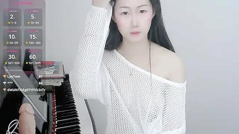 Media: Video of a young Asian woman with long black hair, wearing a white mesh off-shoulder top, in a minimalistic room with a mirror and a black chair.