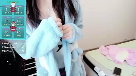 Media: A video of a young woman with long dark hair in a light blue bathrobe, holding a towel, standing next to a desk with pink towels.