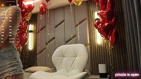 Media: A video depicts a modern bedroom with a white leather armchair, red heart-shaped balloons, and a woman in a blue dress.