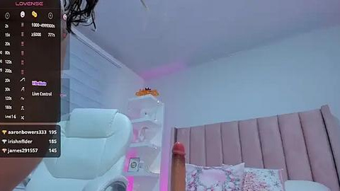 Media: Video of a modern bedroom with a large, plush white cat-shaped toy, pink cushioned headboard, and purple LED lights.