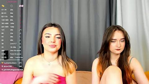 Media: Video of two young women, one with light skin and long brown hair, the other with darker skin and long brown hair, sitting side by side on a couch.