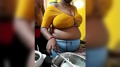 Media: A video of a plus-sized Black woman in a yellow off-the-shoulder top and blue jeans, washing dishes in a kitchen, blurred background, casual setting.