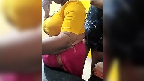 Media: Video of a woman with a curvaceous physique in a bright yellow crop top and tight magenta shorts, leaning against a wall in a public setting, surrounded by blurred figures.