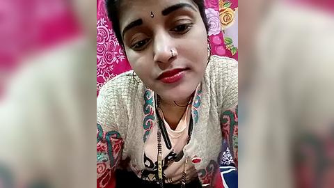 Media: A video of a young woman with medium skin tone, wearing traditional Indian clothing with colorful embroidery, a nose ring, and a bindi, smiling and gazing upwards.