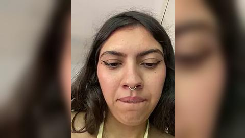 Media: A video of a young woman with long, dark hair, a nose ring, and black eyeliner, making a duck face. Background is blurred, focusing on her facial expression.