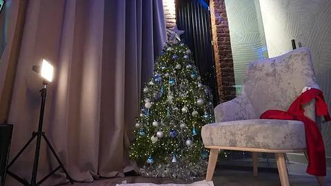 Media: Video of a cozy living room with a decorated Christmas tree, a plush armchair, and a floor lamp, illuminated by warm, ambient lighting.