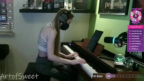 Media: Video of a young woman with fair skin and long brown hair, wearing a black face mask, a striped crop top, and high-waisted jeans, playing a keyboard in a dimly lit room.