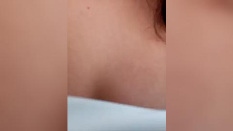 Media: A close-up video of a fair-skinned woman's bare chest, with visible breasts, partially covered by a white towel, and a glimpse of her brown hair. The image focuses on the upper torso, emphasizing the natural skin texture and subtle details.