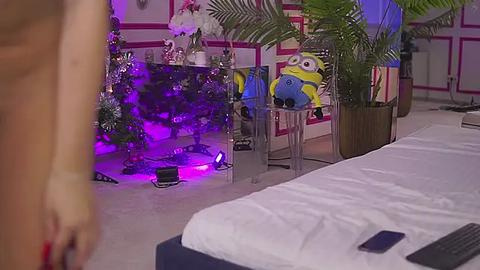 Media: Video of a dimly lit, festive bedroom with purple lights, plush toys, and a bed in the foreground, featuring a partially visible person on the left.