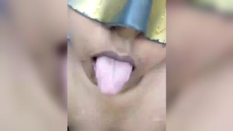 Media: A blurred video of a person with light skin, wearing a shiny golden mask with blue accents, sticking out their tongue. The image is out of focus, making the person's identity and details indistinguishable.