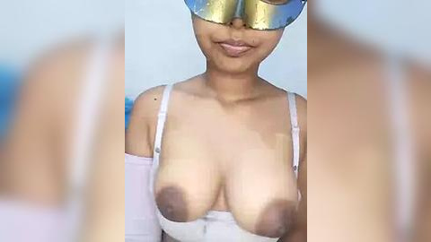 Media: Video of a smiling, light-skinned woman with medium-sized breasts wearing a white off-shoulder top and reflective sunglasses, partially revealing her nipples.