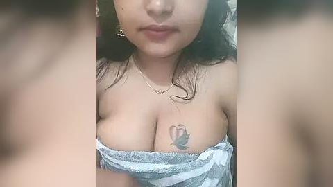 Media: Video of a young Asian woman with medium skin tone, long black hair, wearing a blue and white striped off-shoulder top, revealing cleavage and a butterfly tattoo on her chest.