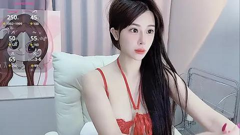 Media: A video of an East Asian woman with long black hair, wearing a red lace bra, sitting on a white couch. The background shows a virtual reality headset and a temperature display.