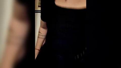 Media: Video of a person wearing a black t-shirt with a tattoo on their arm, partially visible, against a blurred background.