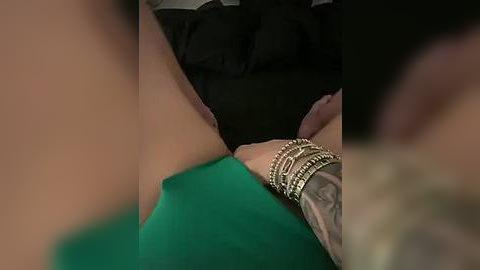 Media: A close-up video shows a tattooed arm wearing a green bracelet and a black dress, with a blurred background.