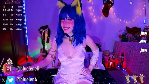 Media: A video of a young woman with blue hair and cat ears, wearing a white, lace-trimmed nightgown, sitting on a bed with plush toys. The room is dimly lit with purple and blue lights, and a video game interface is displayed.