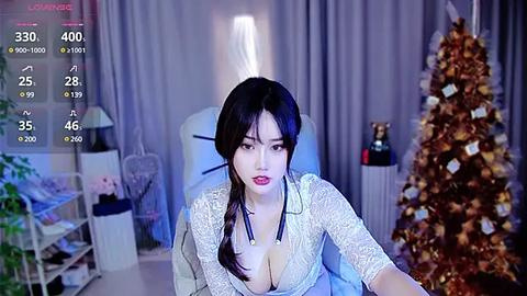 Media: A video shows an Asian woman with long black hair in a white lace blouse, standing in a dimly lit living room with a decorated Christmas tree, a lamp, and a modern chair.