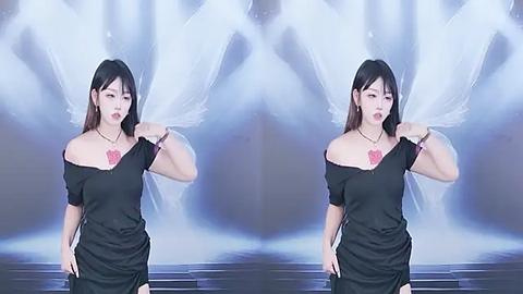 Media: Video of an Asian woman with long black hair, wearing an off-shoulder black dress and red pendant, standing in front of a misty, ethereal background, with a mirror effect.