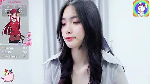 Media: A video of a young East Asian woman with long black hair, fair skin, and pink lipstick, wearing a grey coat, in a virtual avatar overlay.