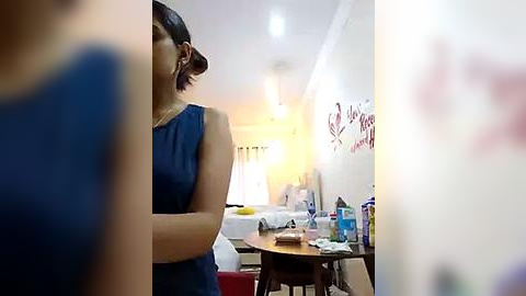 Media: Video of a woman in a blue dress standing near a whiteboard with red text in a brightly lit, minimalistic room.