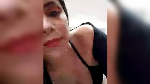 Media: A blurred, grainy video of a woman with a fair complexion, wearing a black dress, her face partially obscured by another person's arm.