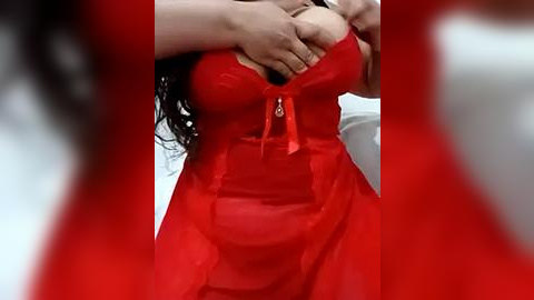 Media: Video of a woman in a sheer, red, strapless lingerie dress with a plunging neckline, her breasts partially exposed, and hands covering her breasts.