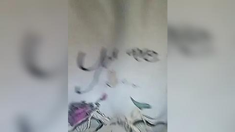 Media: Video of a blurred, pale gray and white surface, possibly a wall or a piece of furniture, with faint, indistinct shapes resembling text or patterns.